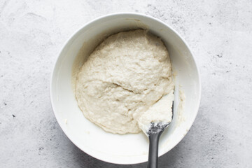 Overhead view of nigerian puff-puff dough that has proofed, puff-puff dough in a white mixing bowl, process of making puff-puff or bofrot