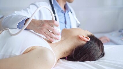 Obraz premium Doctor man is using ultrasound equipment on neck of female patient lying down for a medical examination. Medicine and science