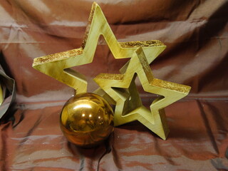 Zwei Holzsterne und eine glänzende, braune Kugel 