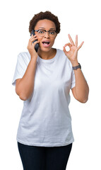 Fototapeta premium Young african american woman talking on the phone over isolated background doing ok sign with fingers, excellent symbol