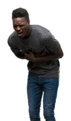 Fototapeta premium Young african american man wearing grey t-shirt with hand on stomach because nausea, painful disease feeling unwell. Ache concept.