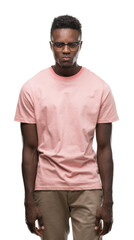 Young african american man wearing pink t-shirt skeptic and nervous, frowning upset because of problem. Negative person.