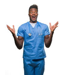 Young african american doctor man over isolated background wearing surgeon uniform celebrating crazy and amazed for success with arms raised and open eyes screaming excited. Winner concept