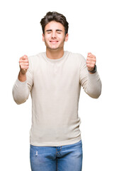 Naklejka premium Young handsome man over isolated background excited for success with arms raised celebrating victory smiling. Winner concept.