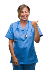 Middle age senior nurse doctor woman over isolated background smiling with happy face looking and pointing to the side with thumb up.