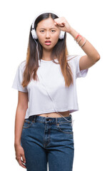 Young asian woman listening to music wearing headphones isolated background annoyed and frustrated shouting with anger, crazy and yelling with raised hand, anger concept