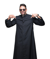 Young Christian priest wearing sunglasses over isolated background looking confident with smile on...