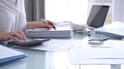 Business woman accountant or auditor reviewing financial data in office. Professional analyzing paper reports and using calculators. Audit and taxes