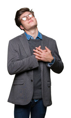 Young handsome business man wearing glasses over isolated background smiling with hands on chest with closed eyes and grateful gesture on face. Health concept.