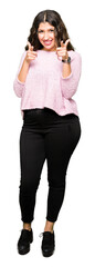 Fototapeta premium Young beautiful woman wearing pink sweater pointing fingers to camera with happy and funny face. Good energy and vibes.