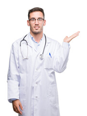 Fototapeta premium Handsome young doctor man smiling cheerful presenting and pointing with palm of hand looking at the camera.