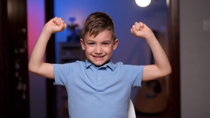 Happy boy raising his arms showing muscles smiling at home © treephwood
