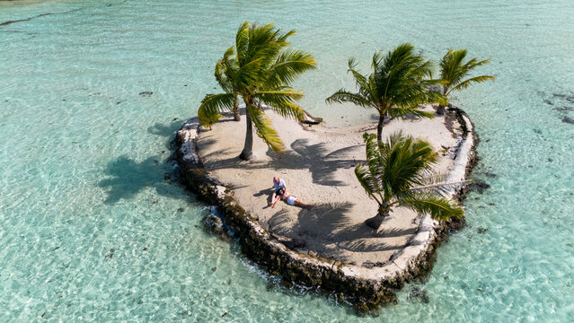 Married couple together on a tropical island in the shape of a heart. The romantic date requires fun travel and adventure. 