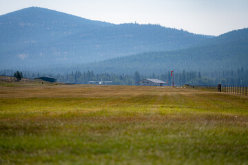 Twin Otter airplane prepares for takeoff from field over pine trees