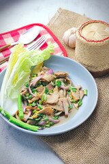Sliced grilled beef salad, Isaan food in Thailand, local food in Thailand. Served with long beans and lettuce On a gray plate served in a Thai restaurant.