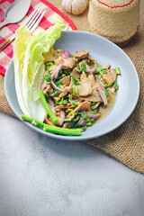 Sliced grilled beef salad, Isaan food in Thailand, local food in Thailand. Served with long beans and lettuce On a gray plate served in a Thai restaurant.