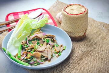Sliced grilled beef salad, Isaan food in Thailand, local food in Thailand. Served with long beans and lettuce On a gray plate served in a Thai restaurant.