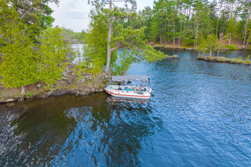 Fototapeta premium Side view of inflatable boat with electric motor anchored at lake wilderness. Summer day and water lake vacation leisure. Perfect spring sport activity for calm relaxation in nature from city hassle.