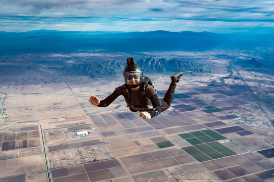 Smiling woman makes skydive alone over Arizona desert mountains and clouds