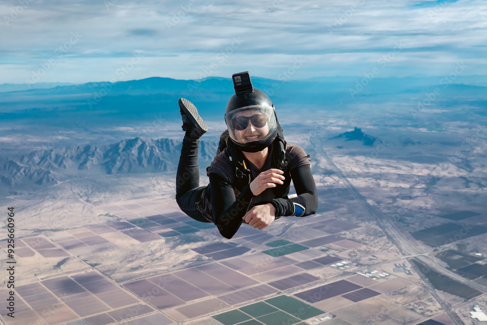 Wall mural smiling woman makes skydive alone over arizona desert