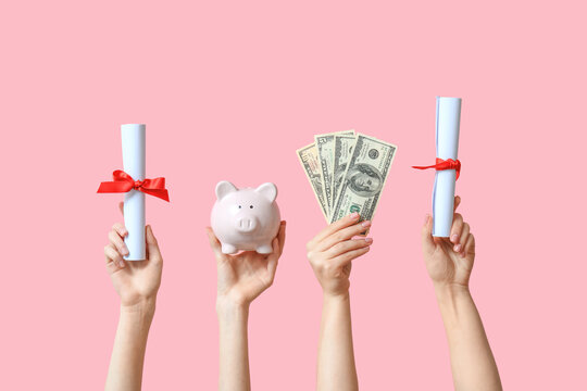Female hands holding diplomas, money and piggy bank on pink background