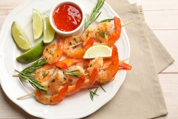 Skewers with delicious grilled shrimps served on wooden table, top view