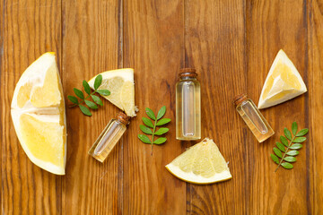 Bottles of cosmetic oil, green leaves and fresh pomelo on wooden background