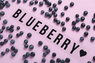 Word BLUEBERRY with sweet fresh berries on lilac background