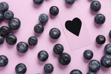 Heart figure with sweet fresh blueberries on lilac background