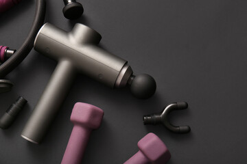 Percussive massager, nozzles and sports equipment on dark background