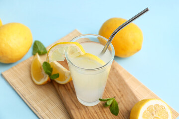 Fototapeta premium Glass of fresh lemonade with mint on blue background