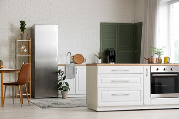 Interior of modern stylish kitchen with fridge, dining table and counter with oven
