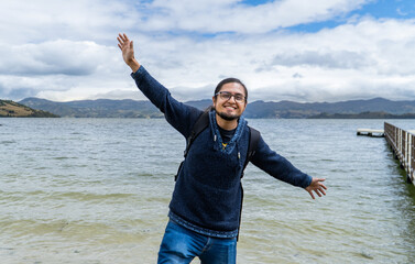 latin man traveler in a natural landscape and lagoon with open arms