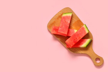 Wooden board with pieces of sweet watermelon on pink background