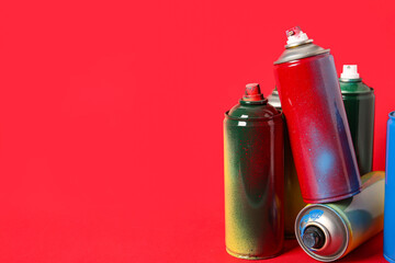 Spray paint cans on red background