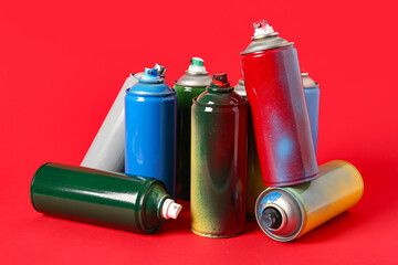 Many spray paint cans on red background