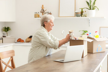 Senior woman with boxes of garbage in kitchen. Waste sorting concept