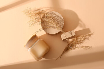 Composition with plaster podiums, jar of cosmetic product and dry reeds on color background © Pixel-Shot