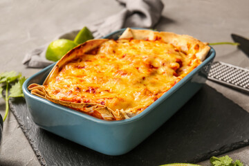 Baking dish with tasty enchilada on table