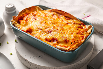 Baking dish with tasty enchilada on light table