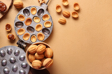 Bowl with tasty walnut shaped cookies and baking form on color background