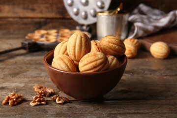 Bowl of tasty walnut shaped cookies on wooden table