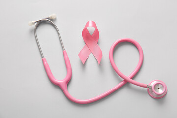 Fototapeta premium Stethoscope and pink ribbon on grey background. Breast cancer awareness concept