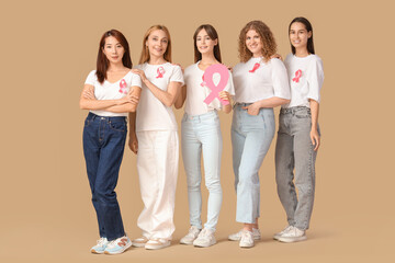 Fototapeta premium Beautiful women with pink ribbons on beige background. Breast cancer awareness concept