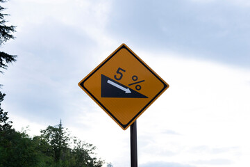 Warning Sign Indicating 5% Downhill Grade: Essential Road Safety Marker for Drivers on Steep Declines in Rural and Mountainous Areas