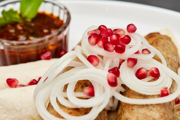 Traditional grilled kebab with pomegranate, onions, spicy sauce for flavorful culinary experience