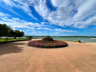 Park riverfront lakefront river lake landscaping flowers bushes blue sky clouds walking paths