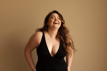 Naklejka premium A young woman with long brown hair laughs joyfully, wearing a black sleeveless top.