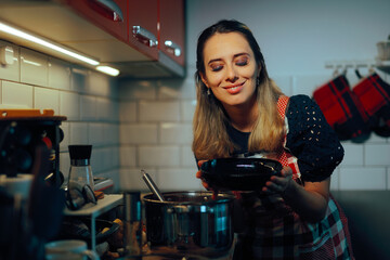 
Happy Woman Holding a Bowl of Homemade Soup in the Kitchen 
Mom preparing the lunch at home feeling joyful
