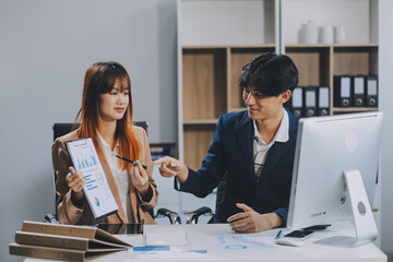 Entrepreneur Asian businessman and businesswoman discussing new business project in tablet in modern Meeting In Modern Office, Asian business casual concept.